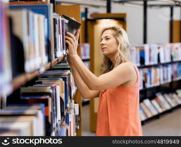 Woman picking a book in public library. That is a difficult choice