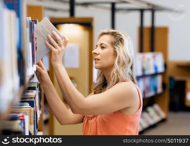 Woman picking a book in public library. That is a difficult choice