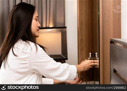 woman picking a perfume bottle from wooden storage cabinet