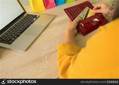 Woman picking credit card in wallet for shopping online.