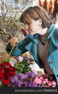 Woman picking up the scent of a Gerbera inside a florist shop