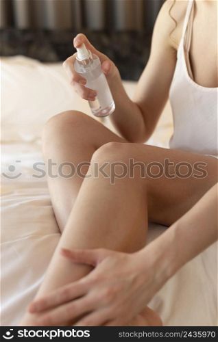 woman pijama home applying lotion body close up