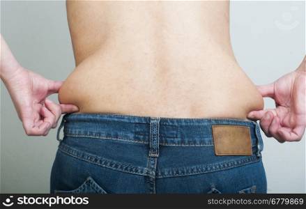 Woman pinching fat from her waist. Back shot