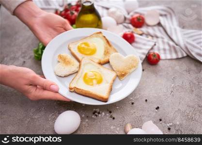 Woman pits plate with Fried Egg on Toast Bread on concrete table for Breakfast.. Woman pits plate with Fried Egg on Toast Bread on concrete table for Breakfast