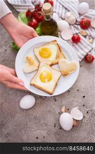 Woman pits plate with Fried Egg on Toast Bread on concrete table for Breakfast.. Woman pits plate with Fried Egg on Toast Bread on concrete table for Breakfast