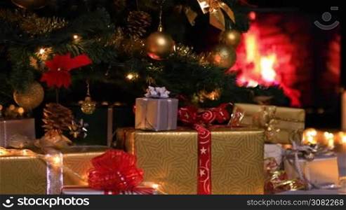 Woman placing gifts under Christmas tree near fireplace. Dolly shot