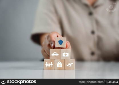 woman placing insurance blocks in the life insurance concept with family, life, car, travel, health and home icons