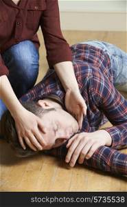 Woman Placing Man In Recovery Position After Accident