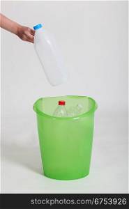 Woman placing plastic bottle into green bin
