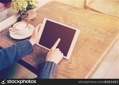 woman play tablet computer in coffee shop with vintage tone.