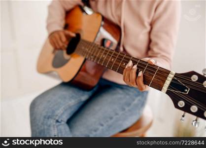 Woman play the guitar at home, closeup view. Pretty lady with musical instrument relax in the room, female music lover resting. Woman play the guitar at home, closeup view