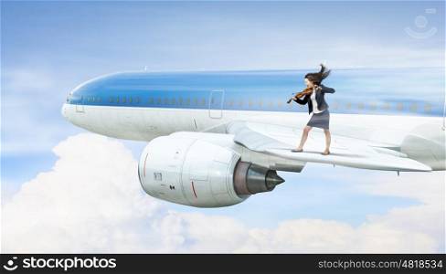 Woman play violin. Young businesswoman standing on edge of airplane wing and play violin