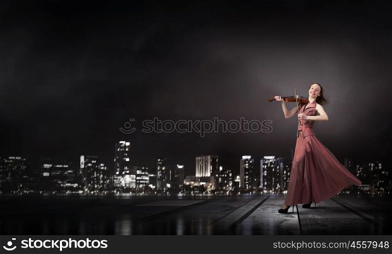 Woman play violin. Young female violin player in long evening brown dress