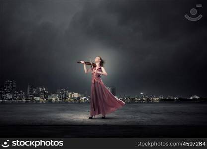 Woman play violin. Young female violin player in long evening brown dress