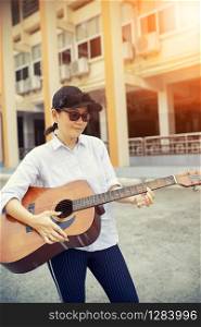 woman playing acoustic guitar on street side