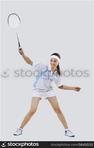 Woman playing badminton isolated over gray background