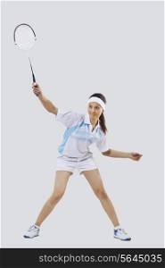 Woman playing badminton isolated over gray background