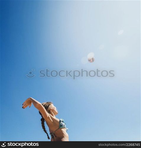 woman playing beach volley with sun background
