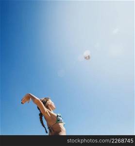 woman playing beach volley with sun background