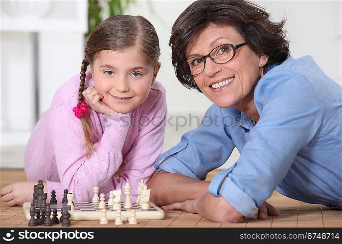 Woman playing chess with little girl
