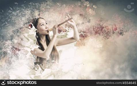 Woman playing fife. Young pretty asian woman in dress playing fife