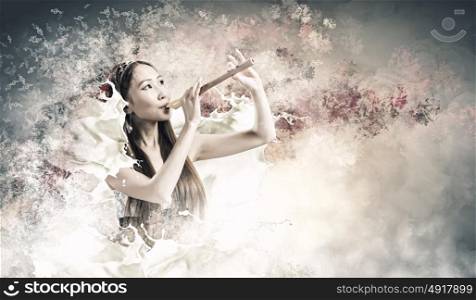 Woman playing fife. Young pretty asian woman in dress playing fife