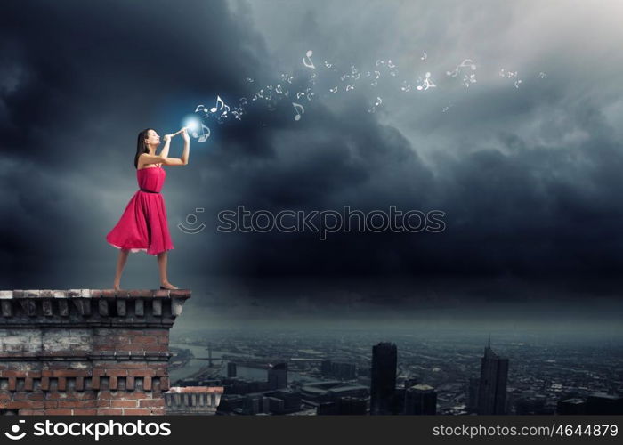 Woman playing fife. Young pretty woman in red dress playing flute