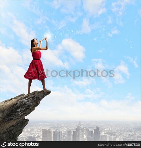 Woman playing fife. Young pretty woman in red dress playing flute