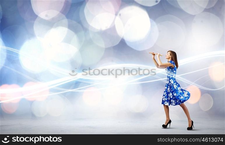 Woman playing fife. Young woman in blue dress playing fife against bokeh background