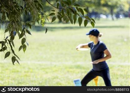 Woman playing flying disc golf sport game in the park