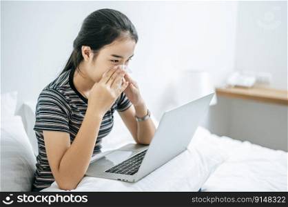 Woman playing laptop and hold a tissue to wipe a nose