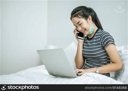 Woman playing laptop and talking on the phone.