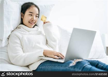 Woman playing laptop and using a credit card to pay for goods online.