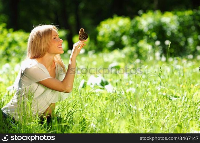 Woman playing with a butterfly on green grass
