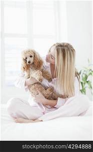 Woman playing with dog on bed