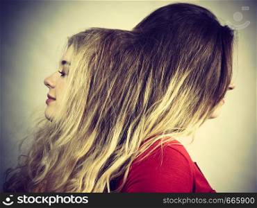 Woman playing with her female friend long brown hair. Different hairdo colors, haircare and hairstyling.. Two women playing with hair