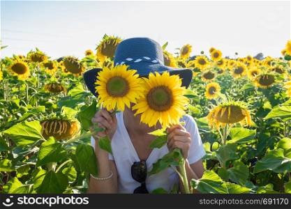 woman playing with two plants of sunflowers
