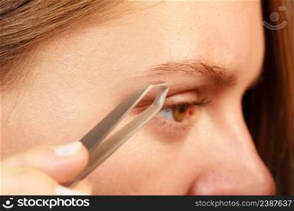 Woman plucking eyebrows depilating with tweezers closeup part of face. Girl tweezing eyebrows.. Woman tweezing eyebrows depilating with tweezers