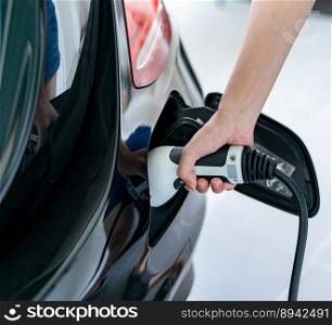 Woman plugged cable charging an electric car at home.