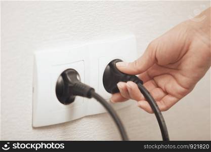 Woman pluging cable to the electric outlet