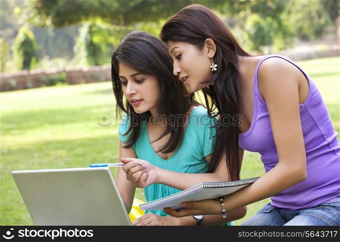 Woman pointing on laptop while taking notes