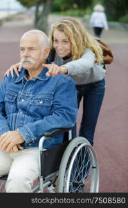 woman pointing out attraction to elderly man in wheelchair