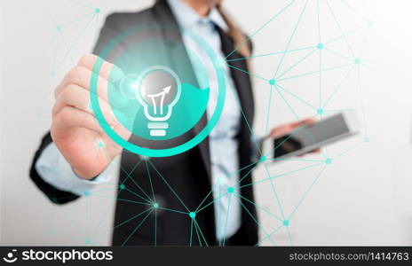 woman pointing screen touching idea lamp icon connection smartphone device. Business woman pointing and touching the screen with an idea lamp circular icon with connections, holding smartphone tablet computer. Office technological devices concept.