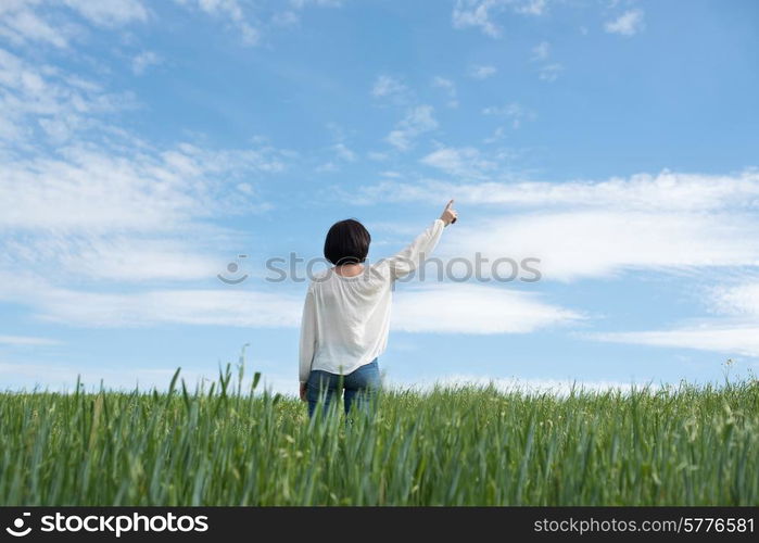 Woman poiting up to copyspace in green field