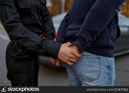 Woman police officer arrest offender, car chief or drug dealer. Closeup view on hand in handcuffs. Police woman arrest offender, view on handcuffs