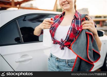 Woman polishes car after washing, polishing process on car-wash. Lady doing wet cleaning of vehicle on self-service automobile wash