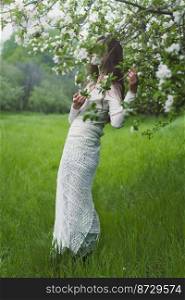 Woman posing in blooming garden scenic photography. Blossoming trees. Picture of woman with forest on background. High quality wallpaper. Photo concept for ads, travel blog, magazine, article. Woman posing in blooming garden scenic photography