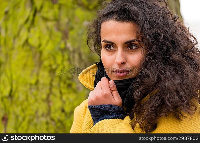 Woman posing in coat with tree trunk at the park