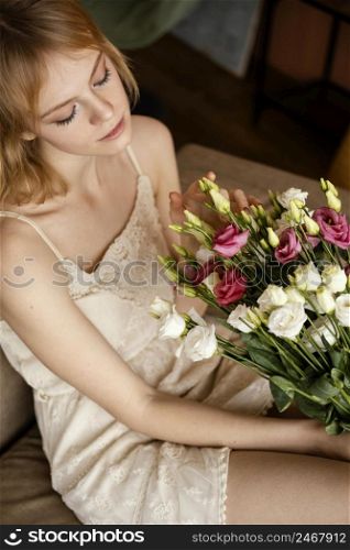 woman posing sofa while holding bouquet spring flowers