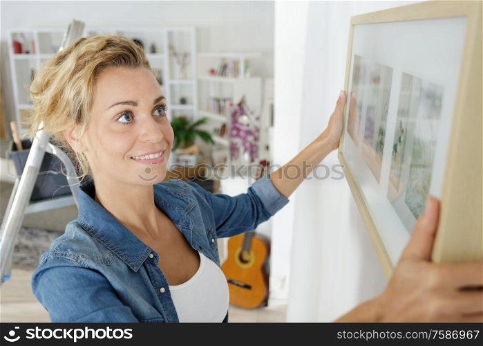 woman positioning picture frame on wall
